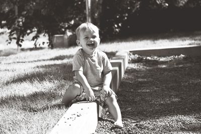 Cute boy smiling while sitting on curb