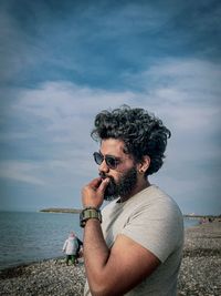 Side view of young man drinking water against sea