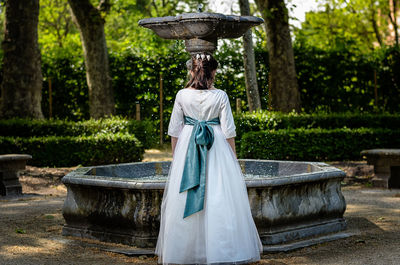 Rear view of girl standing in front of fountain in park