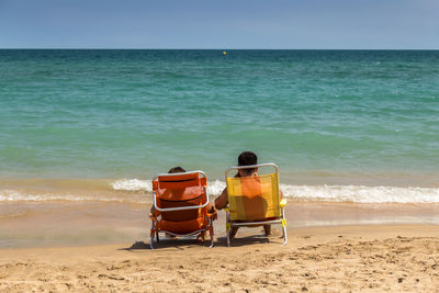 Rear view of chair on beach against sky