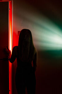 Rear view of woman standing against illuminated wall