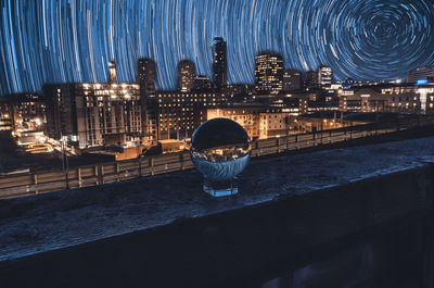 Illuminated city by sea against sky at night
