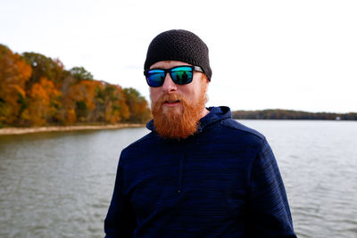 Portrait of bearded man standing against lake