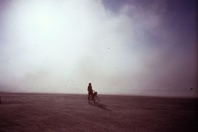 Man riding bicycle on road against sky