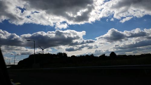 Silhouette of wind turbine against cloudy sky