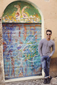 Full length portrait of smiling man standing against wall