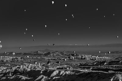 Hot air balloons flying over field against clear sky