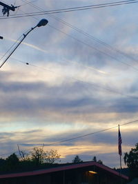 Low angle view of power lines against cloudy sky