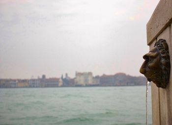 Close-up of statue by sea against sky