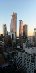 Modern buildings in city against sky during sunset