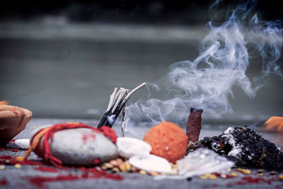 Close-up of incense emitting smoke by religious offering