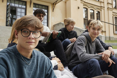 Teenagers sitting in front of school