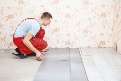 Man putting hardwood floor panels in home