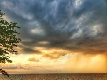 Scenic view of sea against dramatic sky during sunset