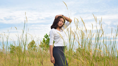 Woman looking away while standing by plants against sky