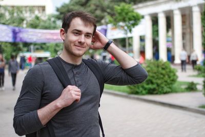 Young man with hand in hair standing in city