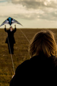 Rear view of woman holding umbrella on field