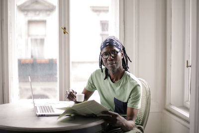 Mature man with laptop and coffee cup sitting at home