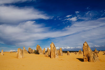 View of sand dunes in desert against cloudy sky