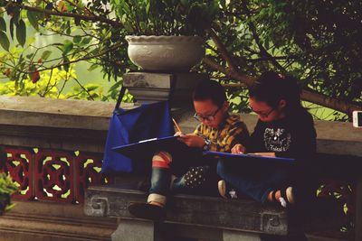 Children studying while sitting on bench