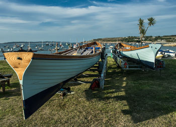 Boats moored on beach against cloudy sky