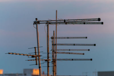 Low angle view of antennae against sky at sunset