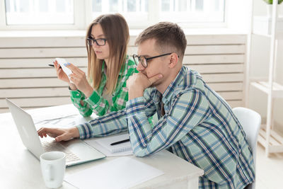 Young woman using phone while sitting on table