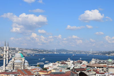 Aerial view of buildings in sea against cloudy sky