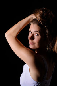 Close-up portrait of young woman against black background