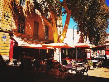 Chairs and tables at sidewalk cafe in city