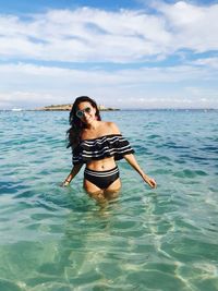 Portrait of woman in bikini in sea against sky