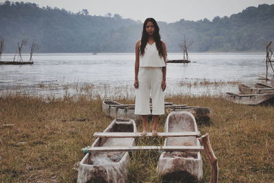 Portrait of young woman standing by lake