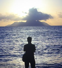 Silhouette man standing by sea against sky during sunset