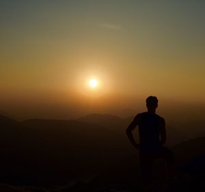 Silhouette man standing on mountain against clear sky during sunset