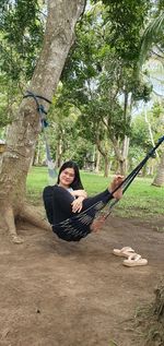 Man sitting on swing at tree
