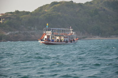 Boat sailing on sea against mountain