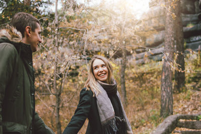 Portrait of smiling young woman standing on land in forest