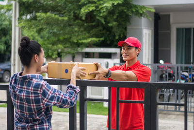 Man delivering package to female customer at gate