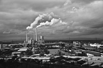 High angle view of smoke emitting from chimney against cloudy sky