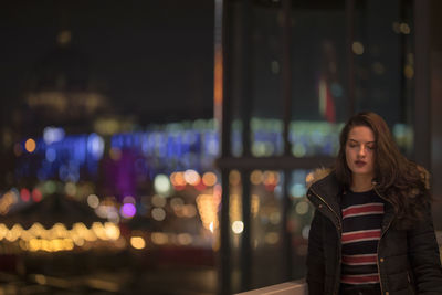 Young woman standing in illuminated city at night
