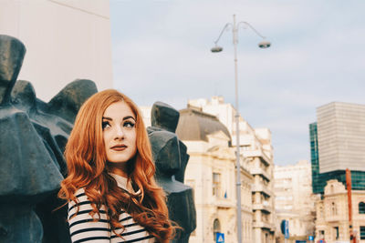 Woman looking away in city against sky