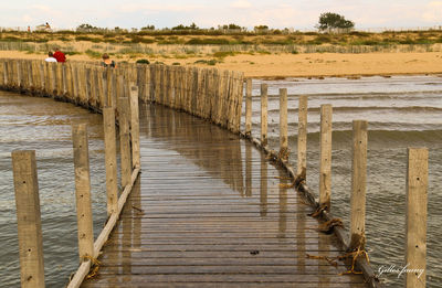 Wooden pier on beach against sky