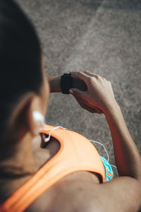 High angle view of female athlete checking time while standing on street