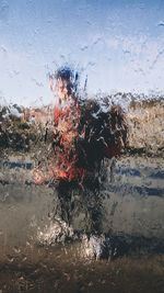 Woman standing on wet shore against sky