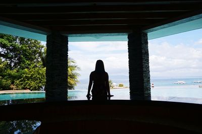 Rear view of woman standing by sea against sky