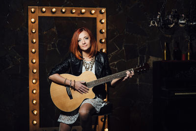 Portrait of young woman playing guitar