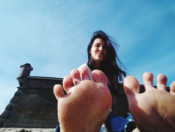 Low angle portrait of young woman against sky