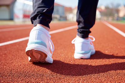 Male runner feet with white sneakers at stadium track, close up. sport sneakers for jogging