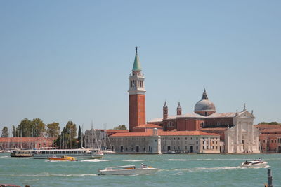 Boats in canal amidst buildings against clear sky