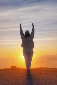 Full length of woman standing on field against sky during sunset